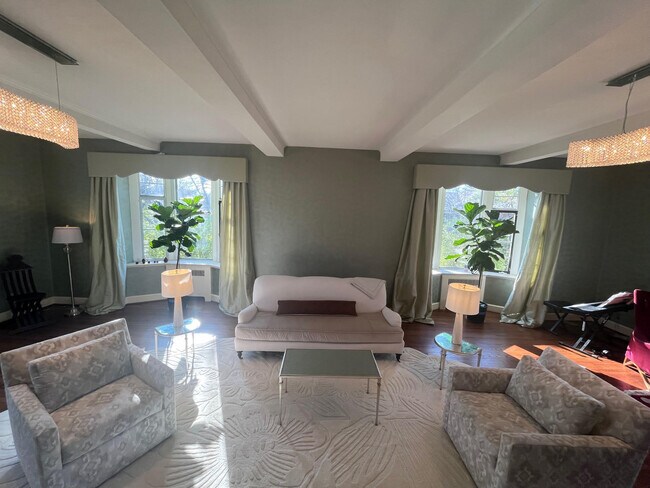 Formal living room with windows on three sides and beamed ceiling - 5553 Little Falls Rd