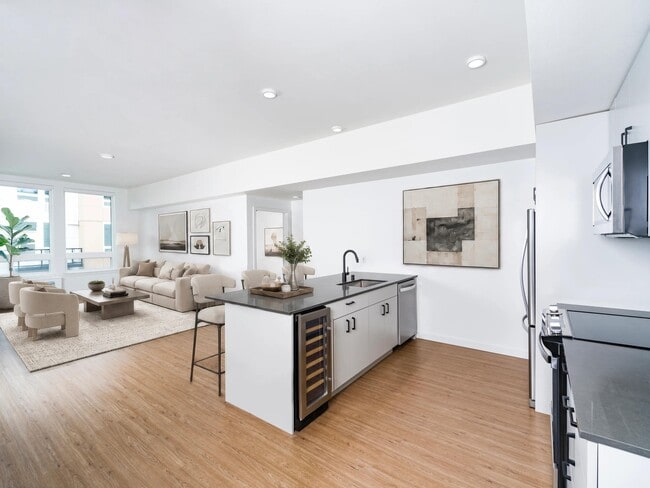 Open-concept kitchen with a center island, built-in wine cooler, and seamless flow into a bright living area filled with natural light