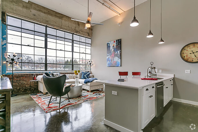 Living room with open concept kitchen, concrete floor, and beautiful white cabinets. Loft style apartment - Lofts at Mockingbird Station Apartments