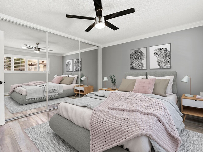 Carpeted bedroom with ceiling fan and large mirrored closet.