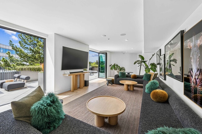 Bright and modern living room with stylish furniture, lush green plants, and a seamless flow to a sunlit outdoor patio. - The Rise Walnut Creek Rental