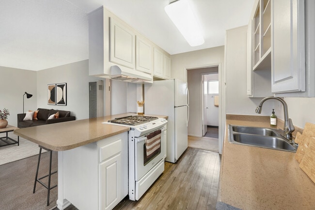 Classic Package I kitchen with white appliances, beige laminate countertops, white cabinetry, and hard surface flooring (select homes)