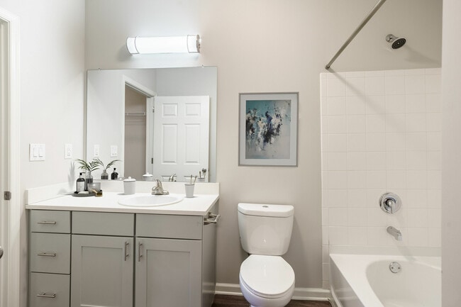 Modern Bathroom with Sleek White Cabinetry, Elegant Wall Art, and a Bathtub for Relaxation.