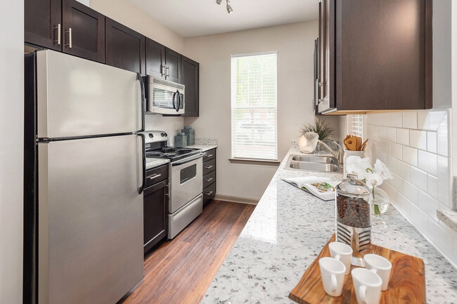 Modern galley kitchen with granite countertops, stainless steel appliances, and sleek cabinetrystylish, functional apartment living in Charlotte. - The District