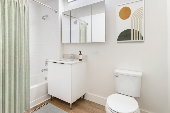 Renovated Package I bath with white marbled quartz countertops, white cabinetry, and hard surface flooring