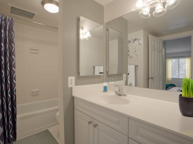 Bathroom with white countertops, white cabinetry and tiled bathtub