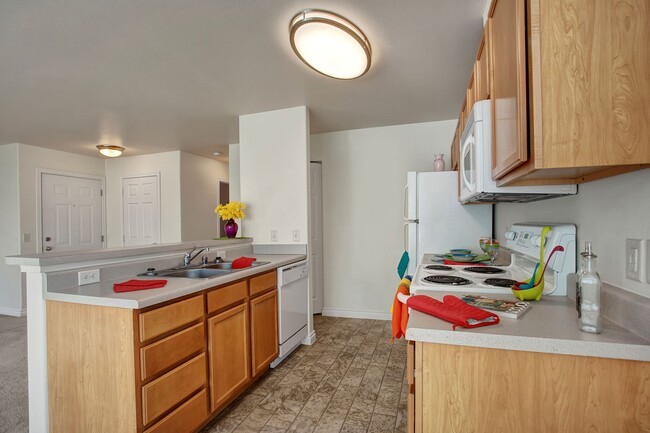 A kitchen with plenty of counter space, a breakfast bar, and lots of cabinet storage space - Lion's Gate Apartments