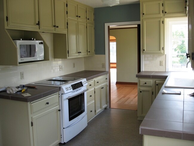 Front-facing kitchen with lots of windows and a dining nook. range, oven, microwave and fridge included.