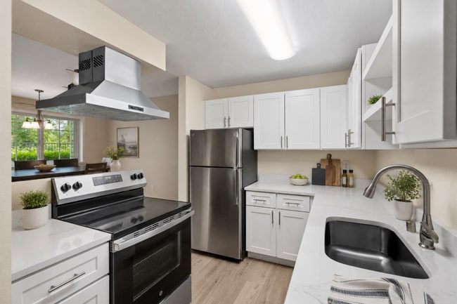 Una cocina luminosa y renovada con acabados modernos, amplio espacio de almacenamiento en los armarios, electrodomésticos de acero inoxidable y vistas abiertas al comedor. - Crossroads at Meridian Apartments