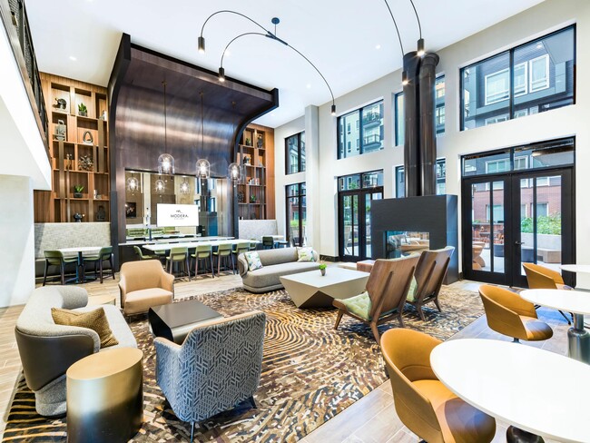Grand community lounge with floor-to-ceiling windows, sculptural fixtures, and a mix of seating areas arranged for hosting, relaxing, and shared moments.