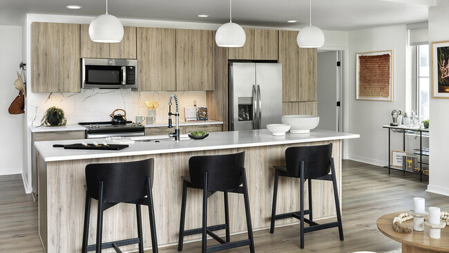 Apartment Kitchen with Stainless Steel Appliances, quartz counters and wood floors. - Griffis LoDo Apartments