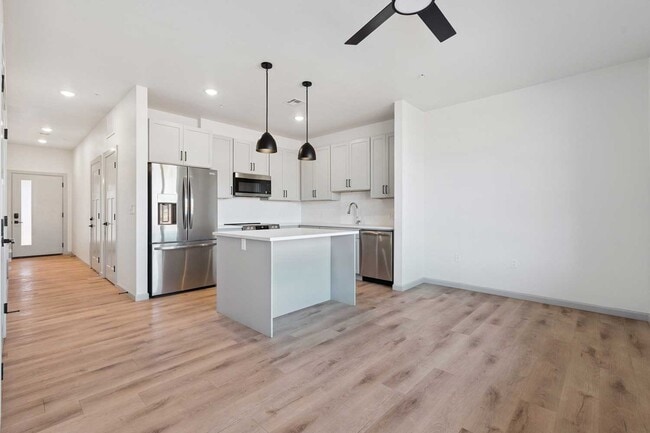 Open concept kitchen with stainless steel refrigerator, dishwasher, microwave, and large center island