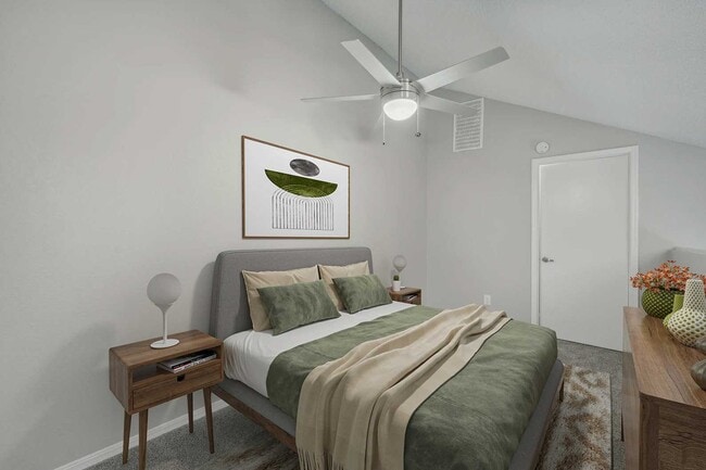 Bedroom with vaulted ceiling, ceiling fan, gray upholstered bed, wood nightstand, framed wall art, and carpet floors
