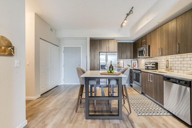 Full Kitchen with Dining Island, Stainless Steel Appliances, and Tile Backsplash - South of Atlantic Luxury Apartments