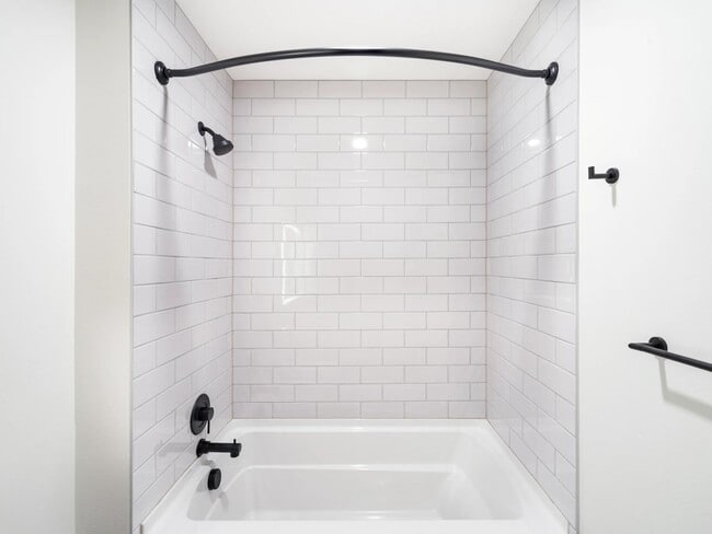 Bathroom with white tile surround, matte black fixtures, and a clean-lined tub and shower design suited to everyday comfort.