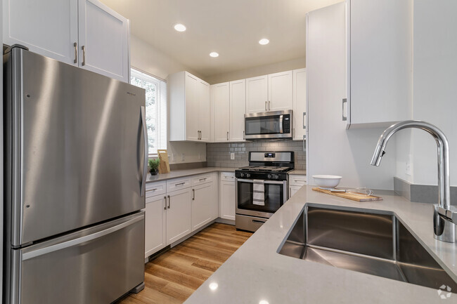 Renovated Package II kitchen with white cabinetry, grey quartz countertops,  grey subway tile backsplash, stainless steel appliances, and hard surface flooring - Avalon Northborough Rental