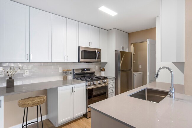 Upgrade Scheme II kitchen with white shaker cabinetry, grey quartz countertops, grey subway tile backsplash, stainless steel appliances, and hard surface flooring