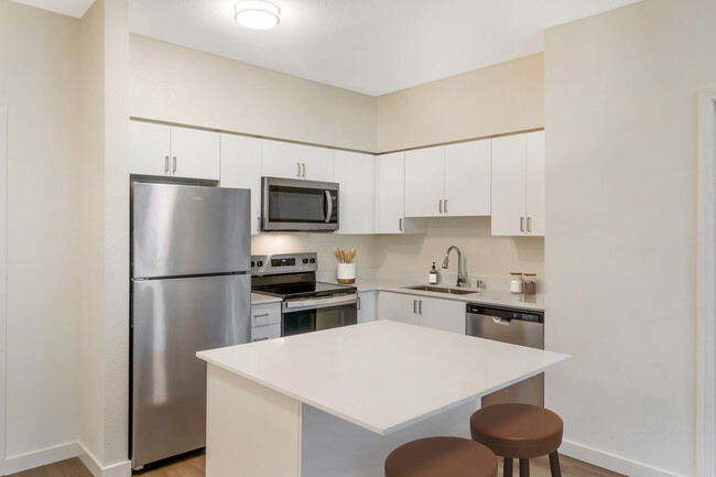 Renovated Package I kitchen with stainless steel appliances, white quartz countertops, white cabinetry, and hard surface flooring - Avalon ParcSquare Apartments