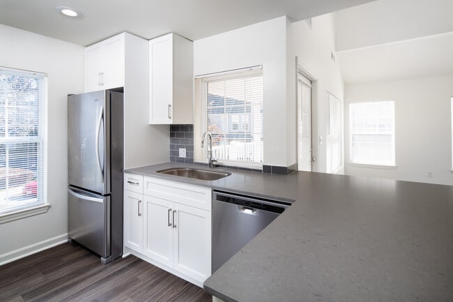 Kitchen with gray quartz countertops, tile backsplash, stainless steel appliances, and upgraded fixtures