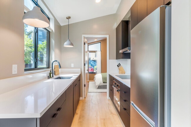 Freestanding home kitchen with stainless steel appliances, white quartz countertops, black cabinetry, and hard surface flooring