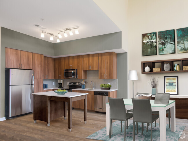 Upgraded dining area and kitchen with walnut cabinetry, white quartz countertops, light grey tile backsplash, stainless steel appliances, and hard surface flooring - Avalon Mosaic Rental