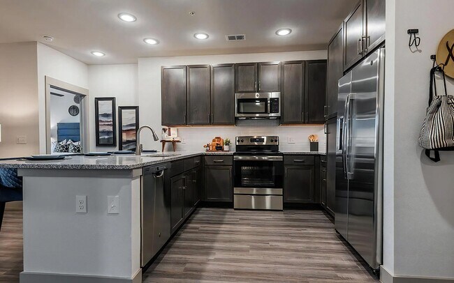Cocina en forma de U con gabinetes oscuros y encimeras de granito - The Harper
