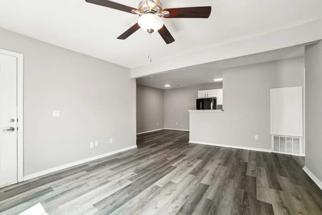 Spacious living and dining area with wood style flooring, ceiling fan, open layout, and breakfast bar overlooking kitchen