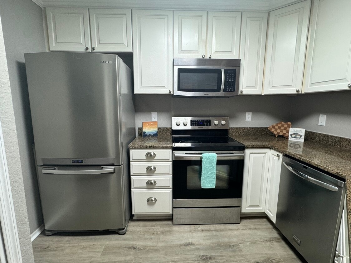 Beautiful white kitchen with crown molding and ceiling height upper cabinets and stainless appliance - 3705 SW 27th St (Gainesville, FL)