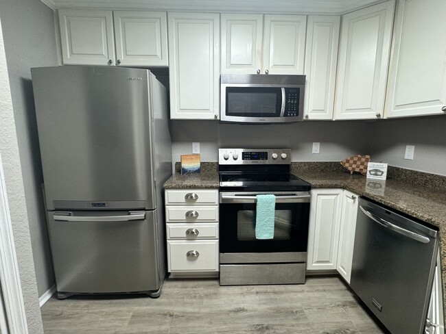 Beautiful white kitchen with crown molding and ceiling height upper cabinets and stainless appliance - 3705 SW 27th St Condominio Unidad 824