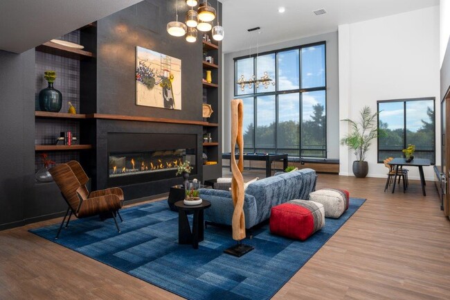 Sleek, modern clubroom with TVs, a fireplace, kitchen, coffee bar, and billiards - Alexan Gateway Apartments