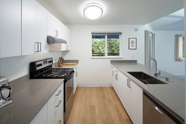 Renovated Package I kitchen with stainless steel appliances, white cabinetry, grey quartz countertops, and hard surface flooring