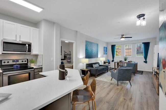 Chic open-concept apartment showcasing a modern kitchen with sleek appliances, a cozy living area with stylish decor, and abundant natural light through large windows.