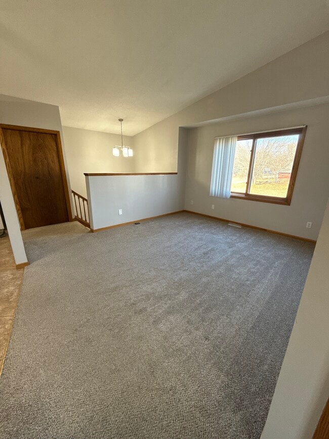 Spacious upper-level living room with vaulted ceilings and large window for natural light. - 9092 Goldenrod Ln N