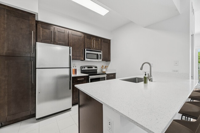 Renovated Package II kitchen with stainless steel appliances, tile backsplash, quartz countertops, and oak cabinetry (in most homes)