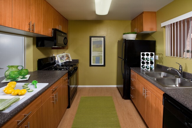 Classic Package kitchen with black appliances, grey speckled laminate countertops, oak cabinetry, and hard surface flooring