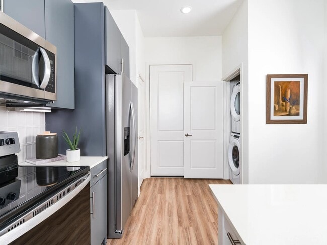 Mejore la elegancia de su cocina con el grifo Chrome Symmons que cuenta con un rociador desplegable, perfectamente complementado por un elegante protector contra salpicaduras de azulejos en Modera Garden Oaks. - Modera Garden Oaks