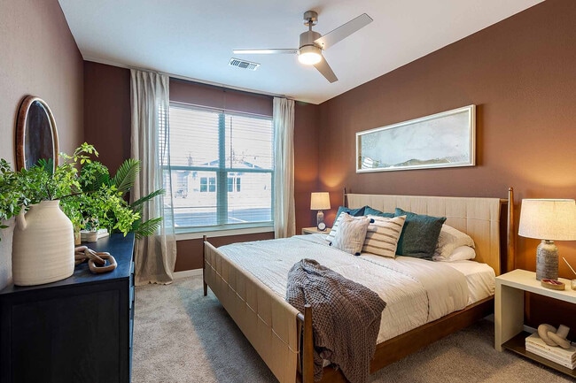 Retreat to a restful bedroom featuring a rich accent wall, plush carpeting, and a large window that fills the room with natural light.