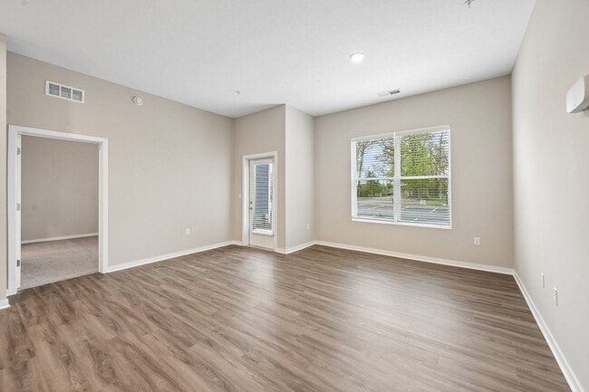 Living area with wooded view and patio of an available floor plan at Flats of Sugar Run luxury apartments in Delaware, OH.