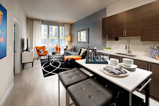 Living area and open concept kitchen with granite countertops and European-style cabinetry, stainless-steel appliances, movable kitchen island and hard surface flooring
