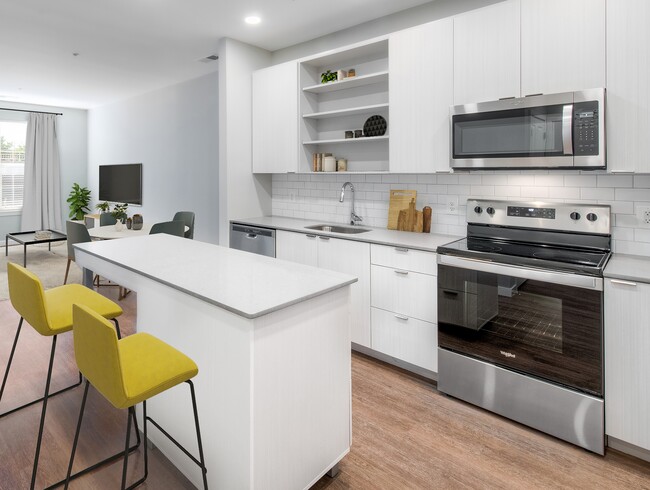 Cocina con encimeras de piedra de cuarzo y gabinetes blancos con placa para salpicaduras de azulejos sobre piso de superficie dura - Kanso Twinbrook Apartamentos