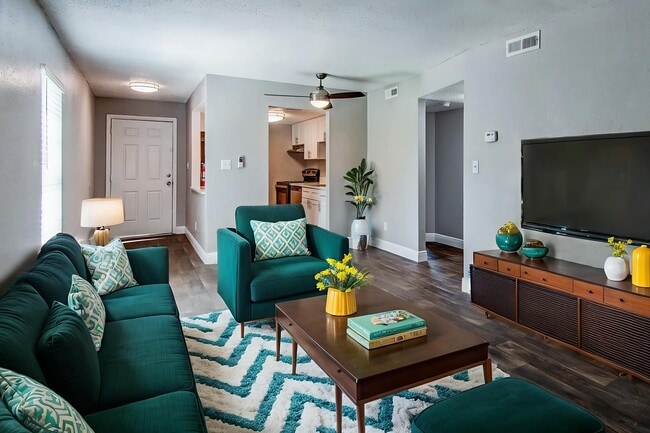 Inviting living room with elegant teal furnishings, a modern patterned rug, and warm natural light creating a cozy ambiance.