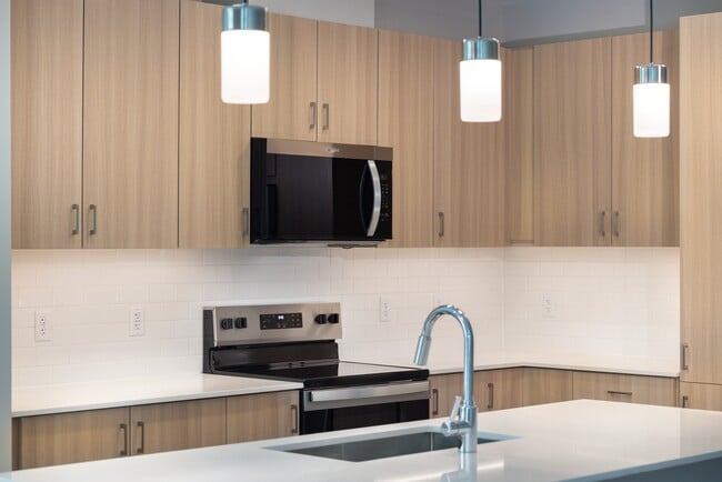 New West Phase - Finish Package IV Kitchen with oak cabinetry, white granite countertops, white tile backsplash, pendant lighting and stainless steel appliances