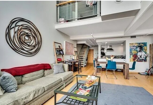 Living room with kitchen/entrance in back, as well as upstairs mezzanine BR - 25 Channel Ctr St Unit 412