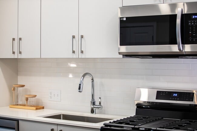 Modern kitchens with stainless steel appliances, white quartz countertops, and light grey cabinetry