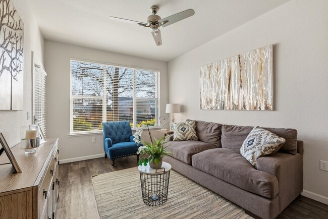 Aspire Apartments Tracy CA A living room with a blue chair and a painting of a tree on the wall.