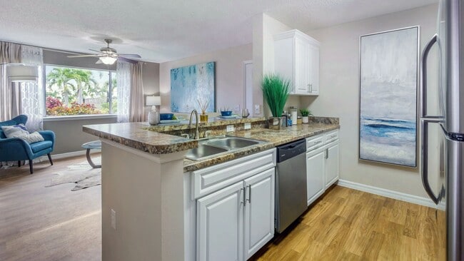 Descubra la calidez y el encanto de las encimeras de cocina doradas Mascarella de Lexington Palms combinadas con gabinetes blancos brillantes y acabados contemporáneos de acero inoxidable.