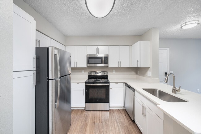 Cook and entertain with ease in a stylish kitchen featuring sleek appliances, granite-inspired countertops, and contemporary details throughout - Pine Lakes Preserve