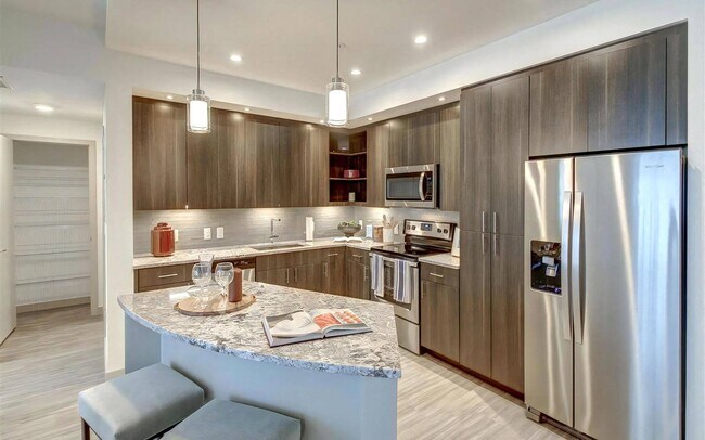 La vista de la cocina incluye barra de bar, iluminación colgante y una entrada con despensa. - Pearl Flagler Village