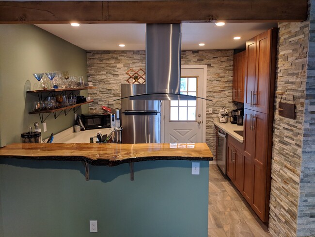 Gorgeous NW inspired kitchen with live edge bar, induction stove, open shelving and rock walls! - 2909 NE 6th St Casa