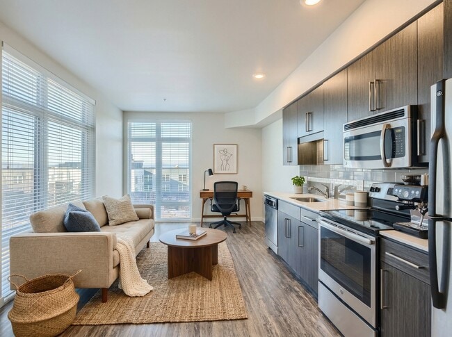 Open layout at 306 Queen Anne in Seattle featuring a linear kitchen with stainless appliances, seating area, and desk nook.